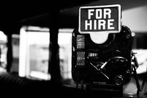a black and white image with a sign in the window saying 'for hire'